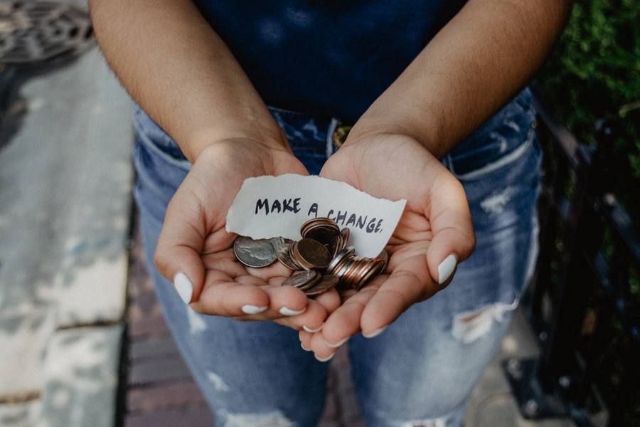 Mains tendant des pièces avec un message « make a change »
